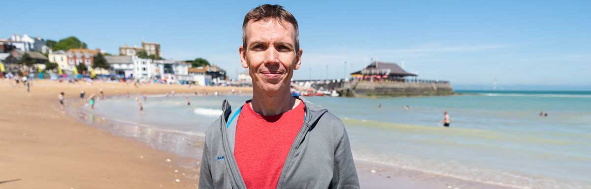 Man holding a photo of a dock with boats on a beach